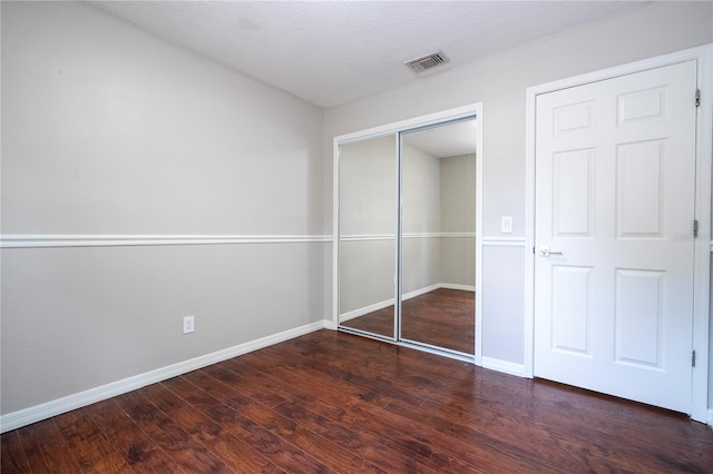 unfurnished bedroom with baseboards, visible vents, a closet, and wood finished floors