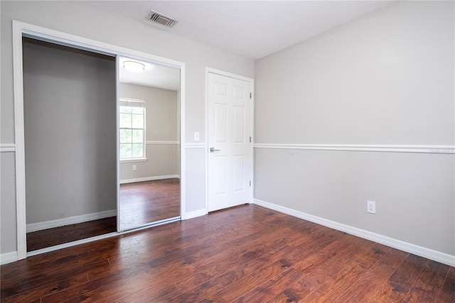 unfurnished bedroom featuring wood finished floors, visible vents, and baseboards