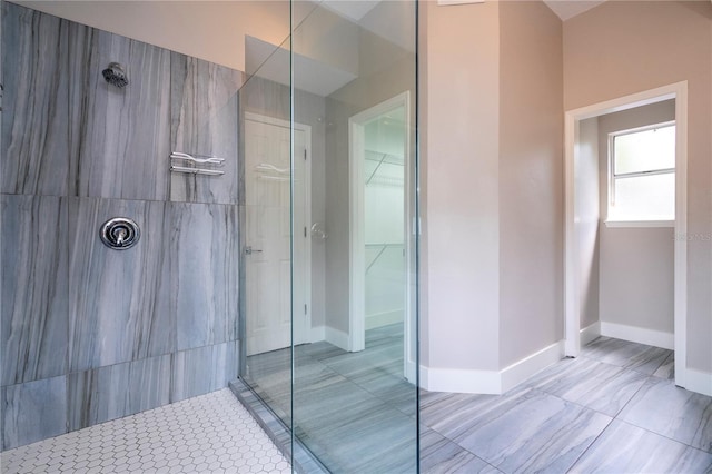 bathroom featuring a walk in shower, a walk in closet, and baseboards