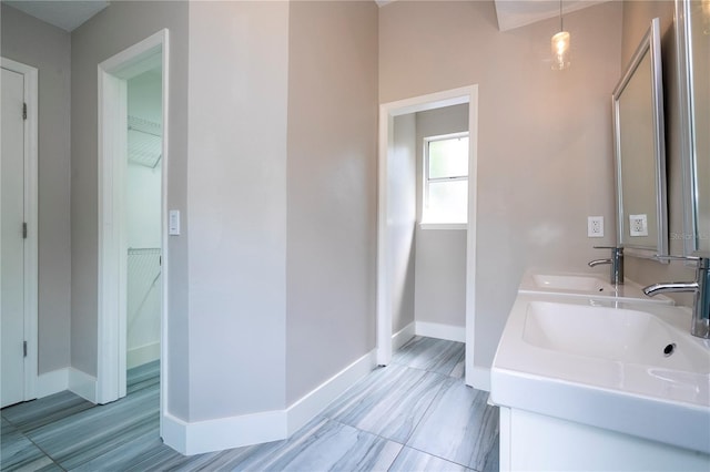 full bathroom featuring a spacious closet, baseboards, and a sink