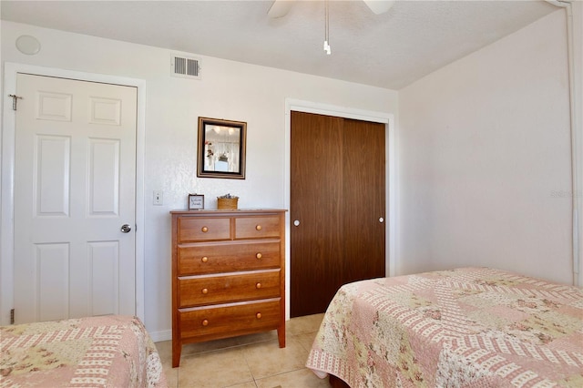 tiled bedroom with ceiling fan and a closet