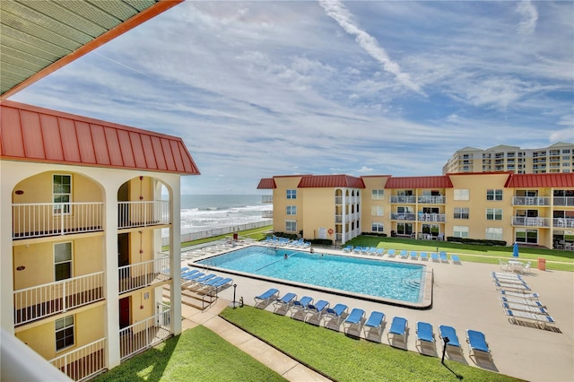 view of swimming pool featuring a patio, a lawn, and a water view