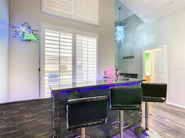 bar with a high ceiling, wood finished floors, and baseboards