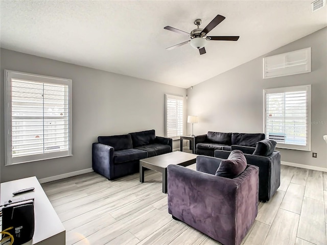 living area with visible vents, baseboards, light wood finished floors, lofted ceiling, and ceiling fan