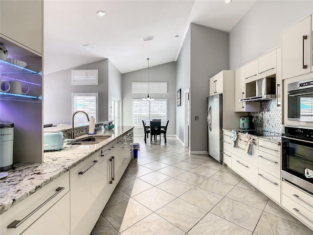 kitchen featuring high vaulted ceiling, a sink, stainless steel appliances, light tile patterned floors, and hanging light fixtures