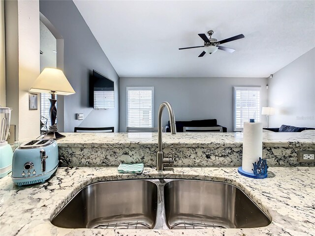 kitchen with ceiling fan, light stone counters, plenty of natural light, and sink