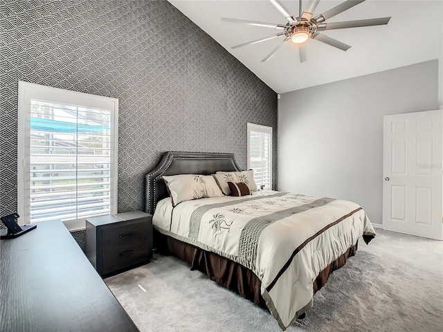 bedroom with wallpapered walls, vaulted ceiling, multiple windows, and light colored carpet