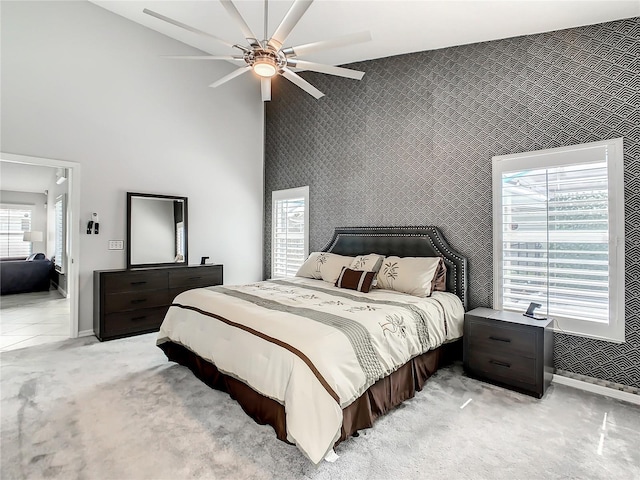 bedroom featuring high vaulted ceiling, multiple windows, light colored carpet, and ceiling fan