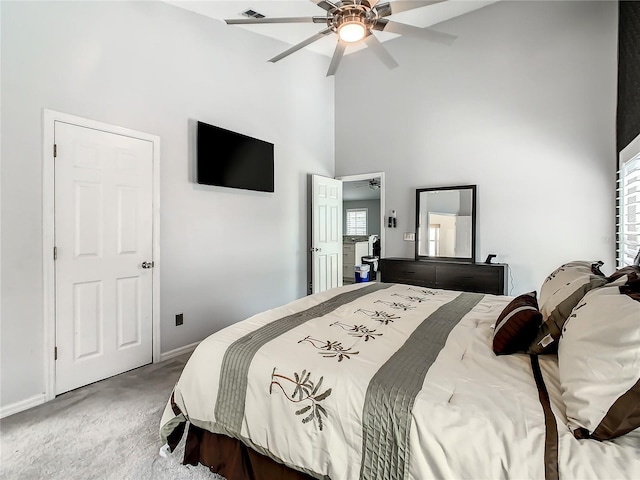 carpeted bedroom with ceiling fan and a towering ceiling