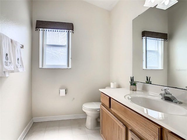 bathroom featuring toilet, vanity, and baseboards