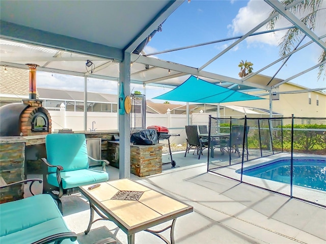 view of swimming pool featuring a lanai, a patio area, a fenced in pool, and an outdoor kitchen