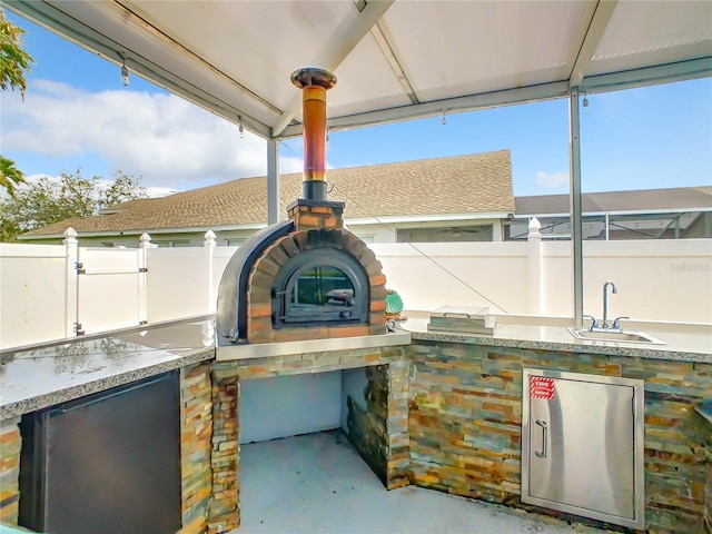 view of patio / terrace with a sink, exterior kitchen, and fence