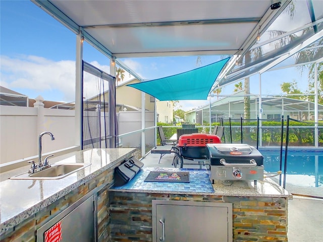 view of patio with glass enclosure, an outdoor kitchen, sink, and a grill