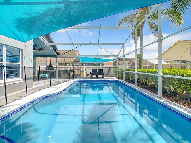 view of swimming pool with glass enclosure, a patio area, and ceiling fan