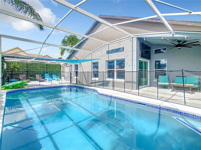 view of pool with glass enclosure, ceiling fan, and a patio