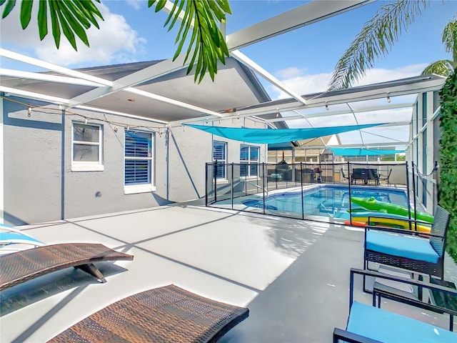 view of swimming pool with a patio area, glass enclosure, a fenced backyard, and a fenced in pool