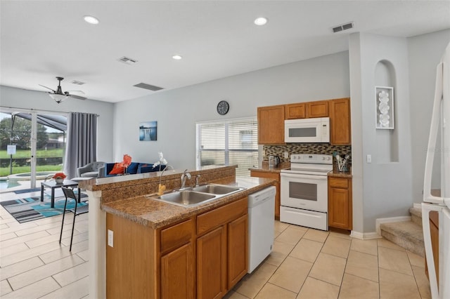 kitchen featuring white appliances, tasteful backsplash, light tile patterned floors, an island with sink, and sink