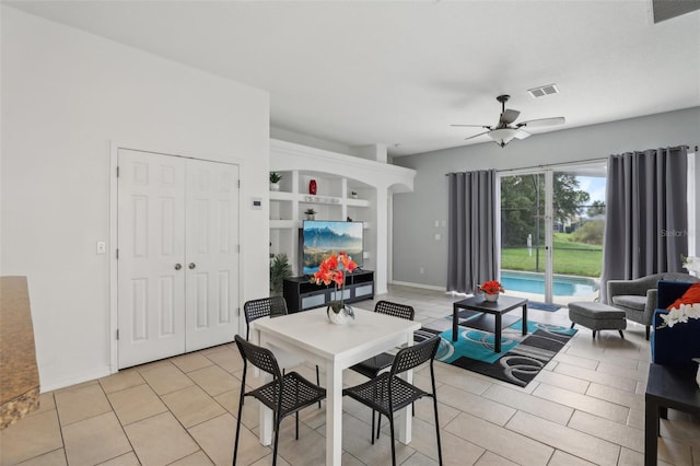 tiled dining space featuring built in shelves and ceiling fan