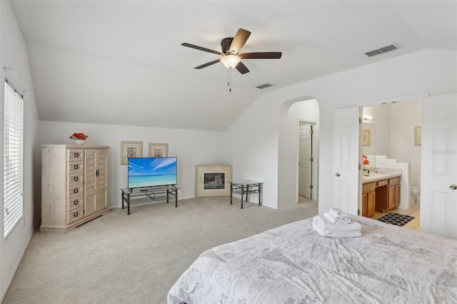 carpeted bedroom featuring vaulted ceiling, connected bathroom, and ceiling fan