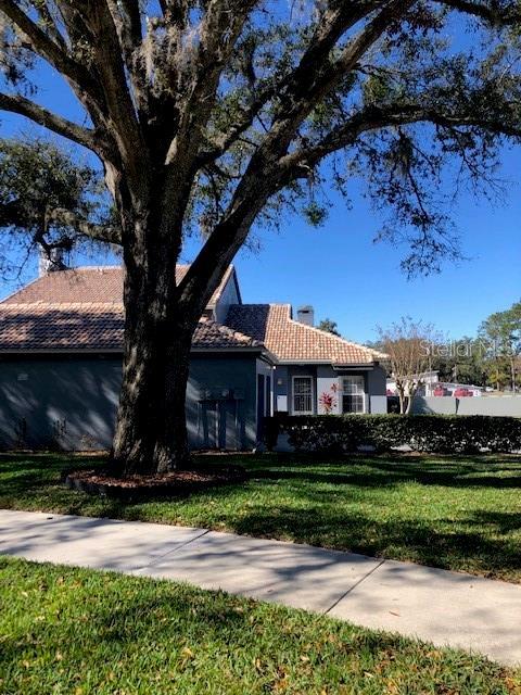 view of side of property featuring a tile roof, a lawn, and a chimney