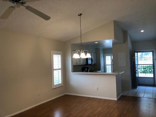 kitchen featuring hardwood / wood-style floors, sink, ceiling fan with notable chandelier, vaulted ceiling, and kitchen peninsula