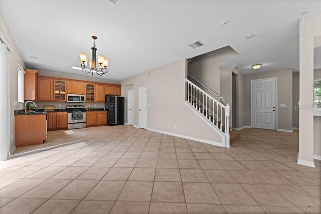 10617 Bamboo Rod Cir, Riverview, FL 33569 - kitchen featuring appliances with stainless steel finishes, dark countertops, a chandelier, brown cabinetry, and glass insert cabinets