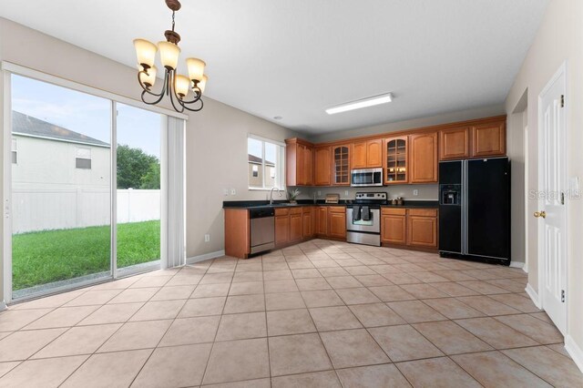 10617 Bamboo Rod Cir, Riverview, FL 33569 - kitchen featuring stainless steel appliances, dark countertops, brown cabinets, a chandelier, and glass insert cabinets