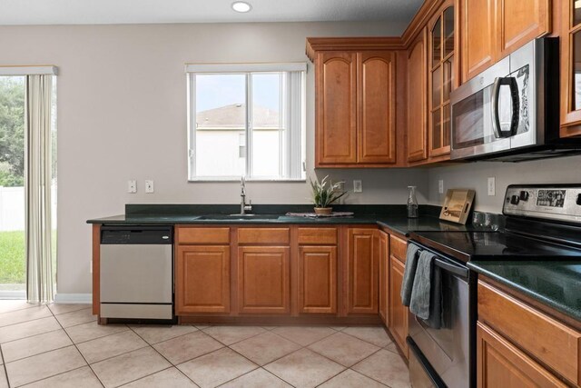 10617 Bamboo Rod Cir, Riverview, FL 33569 - kitchen featuring stainless steel appliances, a sink, brown cabinets, light tile patterned flooring, and dark countertops