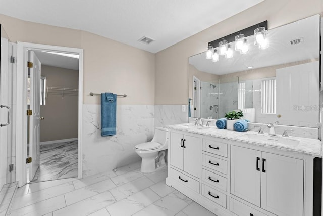 bathroom featuring tile walls, vanity, a shower with shower door, and toilet