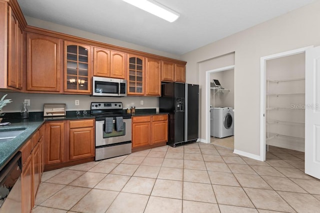 10617 Bamboo Rod Cir, Riverview, FL 33569 - kitchen with appliances with stainless steel finishes, brown cabinets, glass insert cabinets, washer and dryer, and light tile patterned floors
