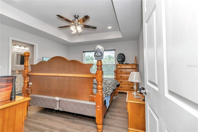 bedroom featuring ceiling fan, wood-type flooring, and a tray ceiling