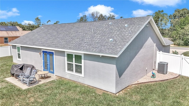 back of house featuring a lawn, a patio, solar panels, and central AC unit