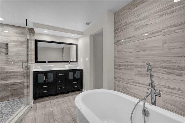 bathroom with a stall shower, visible vents, a sink, and double vanity