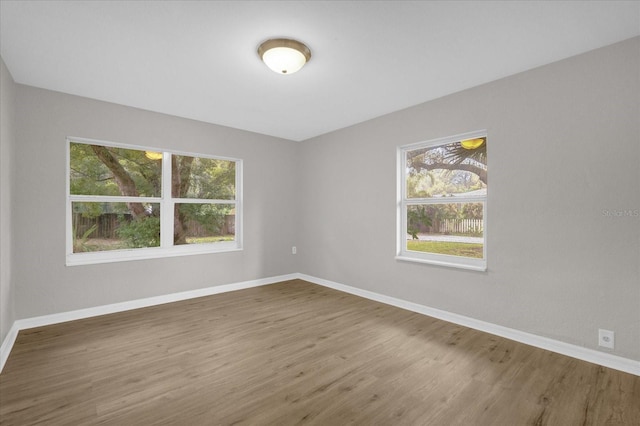 empty room with a healthy amount of sunlight, baseboards, and wood finished floors