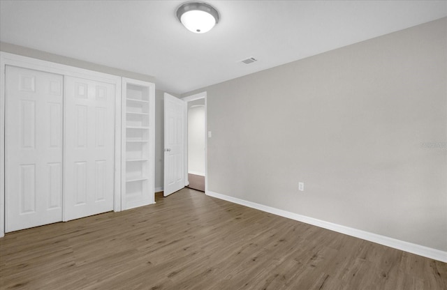 unfurnished bedroom featuring a closet, baseboards, and wood finished floors