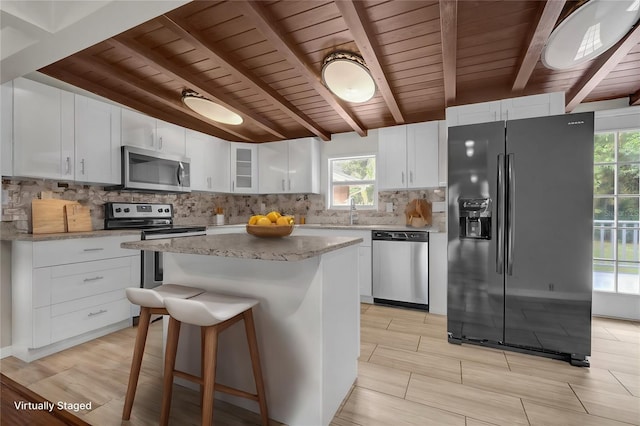 kitchen featuring a center island, stainless steel appliances, tasteful backsplash, glass insert cabinets, and a sink