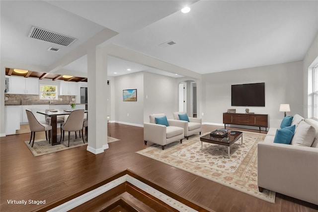 living room with baseboards, visible vents, arched walkways, wood finished floors, and recessed lighting