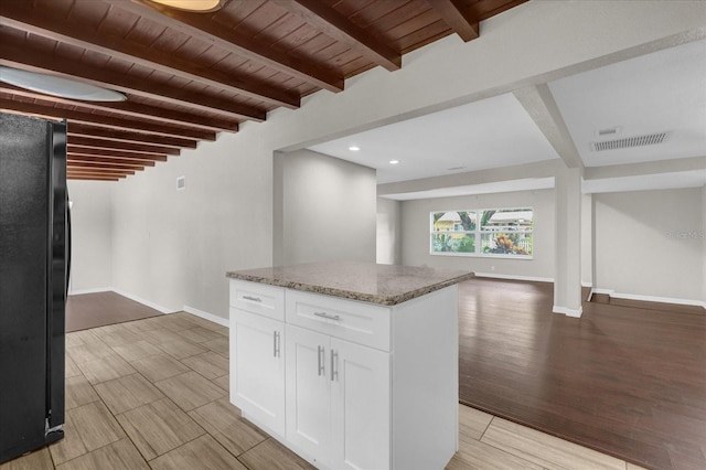 kitchen with light stone counters, freestanding refrigerator, wood ceiling, white cabinetry, and open floor plan