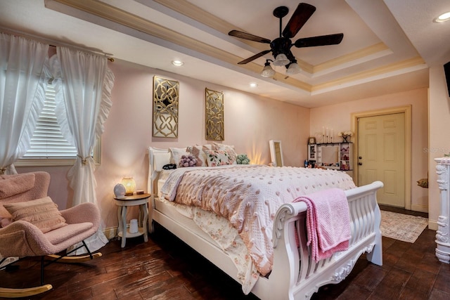 bedroom with a tray ceiling, crown molding, dark hardwood / wood-style flooring, and ceiling fan