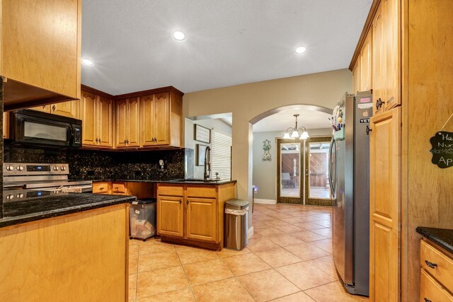 kitchen featuring dark stone counters, tasteful backsplash, light tile patterned floors, sink, and appliances with stainless steel finishes