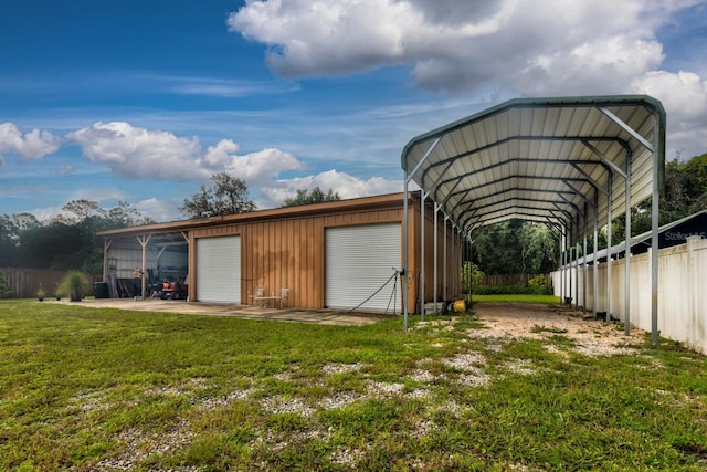 view of outdoor structure featuring a garage, a carport, and a lawn