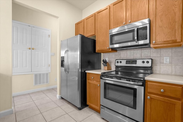 kitchen featuring backsplash, light tile patterned floors, and stainless steel appliances