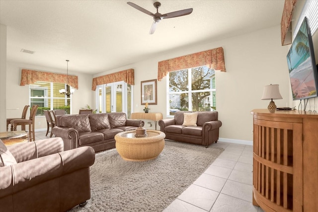 living room featuring a textured ceiling, ceiling fan with notable chandelier, a healthy amount of sunlight, and light tile patterned floors