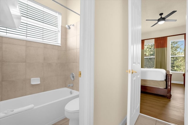 bathroom featuring hardwood / wood-style flooring, ceiling fan, tiled shower / bath combo, and toilet