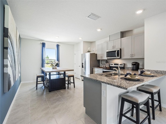 kitchen with a breakfast bar, visible vents, appliances with stainless steel finishes, white cabinets, and a peninsula