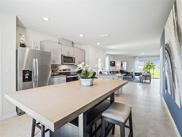 kitchen featuring open floor plan, light tile patterned flooring, gray cabinets, stainless steel appliances, and recessed lighting