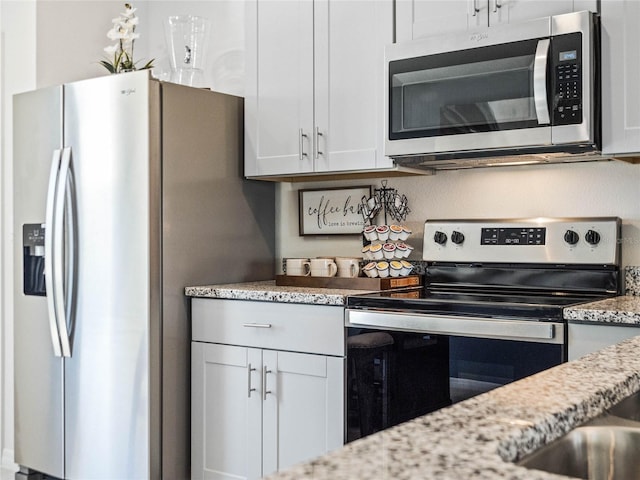 kitchen featuring stainless steel appliances, white cabinetry, and light stone countertops