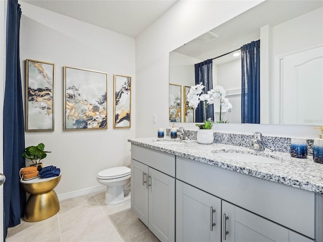 bathroom featuring double vanity, a sink, toilet, and tile patterned floors