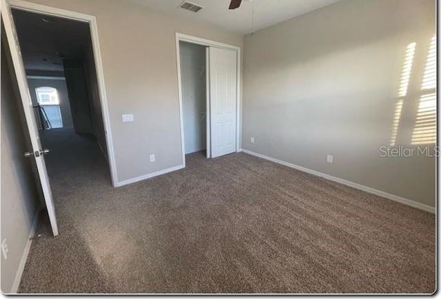 unfurnished bedroom featuring dark colored carpet, ceiling fan, and a closet