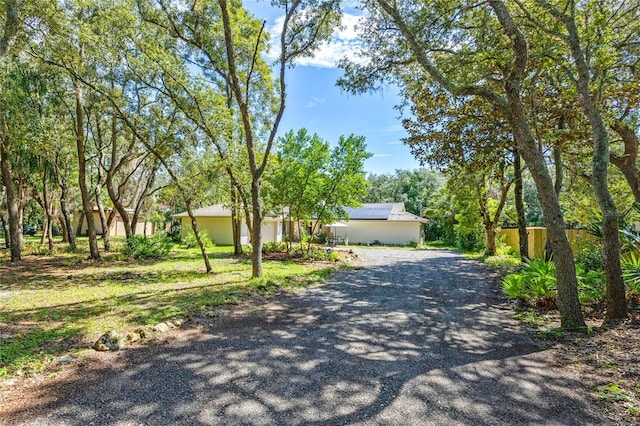 ranch-style house with gravel driveway and roof mounted solar panels